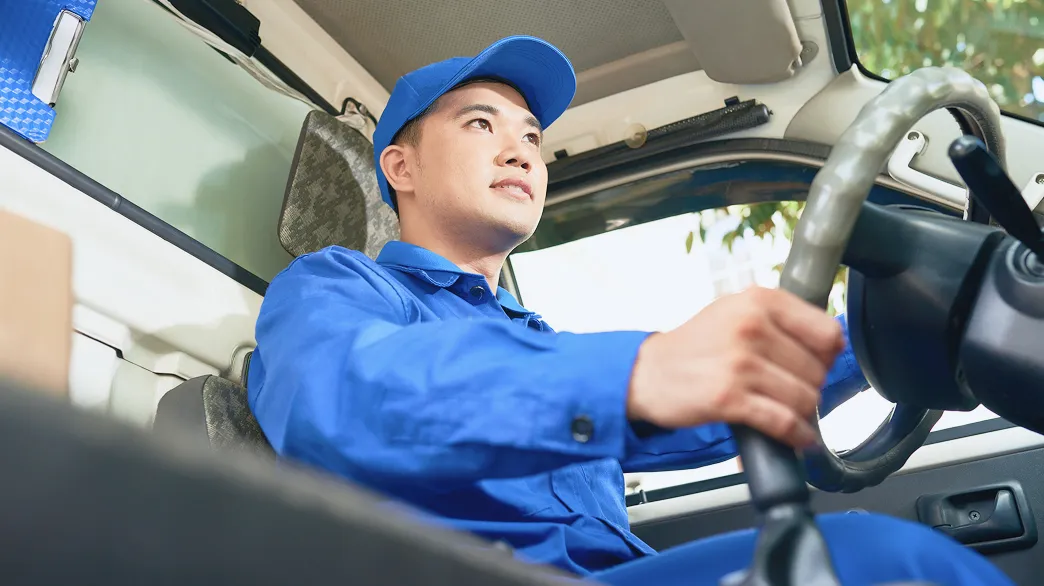 作業服を着た男性が車を運転している様子