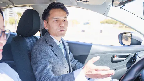 運転教習中にインストラクターが手元のバインダーに記入をしている様子